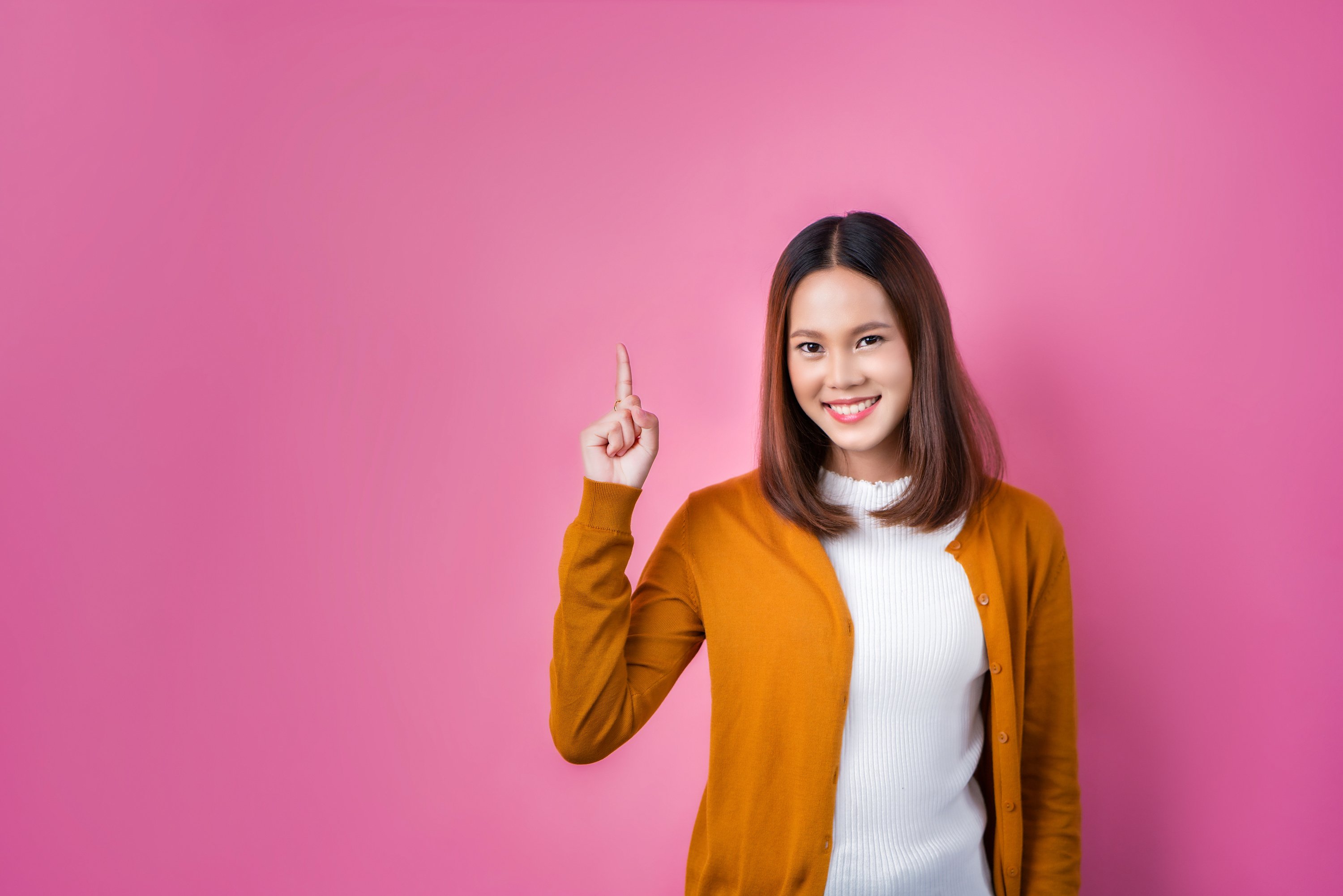 asian woman pointing fingers on pink background